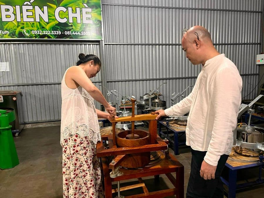 Khách cùng người làm trà trải nghiệm vò trà bằng dụng cụ gỗ tại xưởng